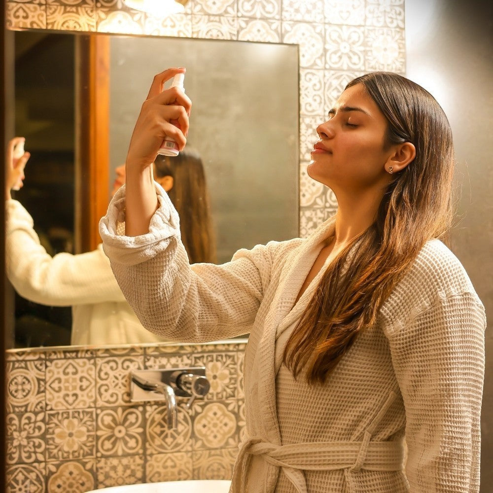 A woman in bathrobe using Serenade Calmplexion face mist for a spa-like ritual.